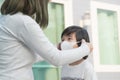 Asian mother puts a safety mask on her son