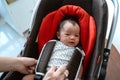 Asian mother putting baby into seat Royalty Free Stock Photo