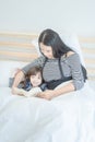 Asian mother reading funny book with her cute daughter Royalty Free Stock Photo