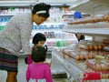 Asian mother showing chicken eggs she wants to buy to her two little daughters at a supermarket Royalty Free Stock Photo
