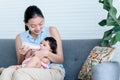 Asian mother sitting on sofa and feeding milk from bottle milk to her baby newborn daughter Royalty Free Stock Photo