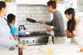 Asian mother, son and daughter watching father tossing pancake for breakfast in kitchen Royalty Free Stock Photo