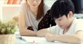 Asian mother with son doing homework in living room. Royalty Free Stock Photo