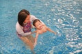 Asian mother take little Asian baby boy in swimming class. Happy toddler enjoying swim in pool with mom