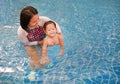 Asian mother take little Asian baby boy in swimming class. Happy toddler enjoying swim in pool with mom