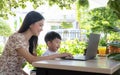 Asian mother teach her son by note book computer in garden at home