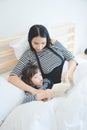 Asian mother teaching her daughter to reading a bed time story book in holiday Royalty Free Stock Photo