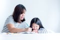 Asian mother is teaching a 6 year old daughter to learn to write and read