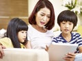 Asian mother and two children using digital tablet together Royalty Free Stock Photo