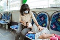 Asian mother wearing a mask along with a daughter who sleeps on a bench
