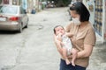 Asian mother wearing surgical face mask holding and looking her little newborn baby, COVID-19 concept Royalty Free Stock Photo