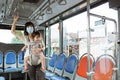 an Asian mother wears a mask and carries her child while standing holding on to the bus Royalty Free Stock Photo