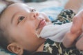 Asian mother is wiping her baby face after infant baby boy vomiting. people and family lifestyle concept Royalty Free Stock Photo