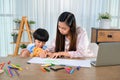 Asian mother work home together with son. Mom and kid drawing picture and color painting art. Woman lifestyle and family Royalty Free Stock Photo