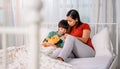 Asian mother work home together with son. Mom and kid reading fairy tale before sleep on the bed. Family lifestyle Royalty Free Stock Photo