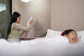 Asian mother working on bed with sleeping daughter by side at home Royalty Free Stock Photo