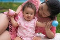 Asian mum and little child - young happy and beautiful Chinese woman playing on city park with adorable and cheerful baby girl in Royalty Free Stock Photo