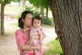 Asian mum and little child - young happy and beautiful Chinese woman playing on city park with adorable and cheerful baby girl in Royalty Free Stock Photo