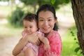 Asian mum and little child - young happy and beautiful Chinese woman playing on city park with adorable and cheerful baby girl in Royalty Free Stock Photo