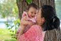 Asian mum and little child - young happy and beautiful Chinese woman playing on city park with adorable and cheerful baby girl in Royalty Free Stock Photo