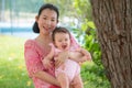 Asian mum and little child - young happy and beautiful Chinese woman playing on city park with adorable and cheerful baby girl in Royalty Free Stock Photo