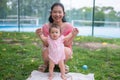 Asian mum and little child - young happy and beautiful Chinese woman playing on city park with adorable and cheerful baby girl in Royalty Free Stock Photo