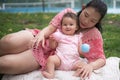 Asian mum and little child - young happy and beautiful Korean woman playing on city park with adorable and cheerful baby girl in Royalty Free Stock Photo