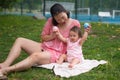 Asian mum and little child - young happy and beautiful Korean woman playing on city park with adorable and cheerful baby girl in Royalty Free Stock Photo