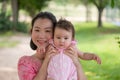 Asian mum and little child - young happy and beautiful Korean woman playing on city park with adorable and cheerful baby girl in Royalty Free Stock Photo