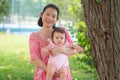 Asian mum and little child - young happy and beautiful Korean woman playing on city park with adorable and cheerful baby girl in Royalty Free Stock Photo