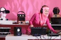 Asian musician standing at dj table wearing headphones while playing techno music at professional turntables Royalty Free Stock Photo