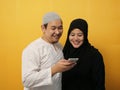 Asian muslim couple shocked or surprised to see something on smart phone, happy expression winning gesture Royalty Free Stock Photo