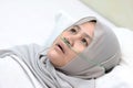 Asian muslim female patient with nasal cannula staying in hospital room alone. Uncomfortable sick woman look pensive lying in bed