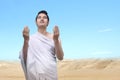 Asian Muslim man in ihram clothes standing and praying while raised arms Royalty Free Stock Photo