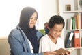 Asian muslim mom angy and punish her boy by pulling his ear due to lazy in his study, mother force her child to reading book, Royalty Free Stock Photo