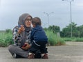 asian muslim mother with her baby sitting on the ground in the city street Royalty Free Stock Photo