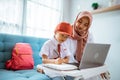 asian muslim primary student with mother sitting together doing homework at home Royalty Free Stock Photo