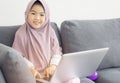 Asian muslim Teenager Surfing Internet with notebook on sofa in living room