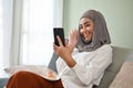 Asian Muslim woman enjoys talking with her friend through a video call on her smartphone Royalty Free Stock Photo