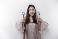 An Asian Muslim woman is fasting and hungry and holding cutlery while looking aside thinking about what to eat Royalty Free Stock Photo