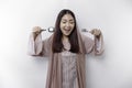 An Asian Muslim woman is fasting and hungry and holding cutlery while looking aside thinking about what to eat Royalty Free Stock Photo