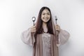 An Asian Muslim woman is fasting and hungry and holding cutlery while looking aside thinking about what to eat Royalty Free Stock Photo