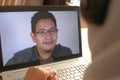Asian muslim woman having video teleconference witha man on her laptop at home, online learning or working from home