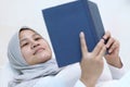 Asian muslim woman reading holy Quran on bed, reciting to memorize Quran before sleep Royalty Free Stock Photo