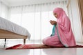 Asian Muslim woman, sitting in order, wears a pink hijab to complete the daily routine of prayer. According to the faith of Islam