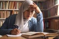 Asian muslim woman studying in library, exam preparation concept. Female college student doing research and making notes in her Royalty Free Stock Photo