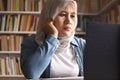 Asian muslim woman studying in library, exam preparation concept. Female college student using laptop to learn online Royalty Free Stock Photo