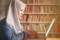 Asian muslim woman studying in library, exam preparation concept. Female college student using laptop to learn online Royalty Free Stock Photo