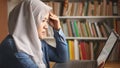 Asian muslim woman studying in library, exam preparation concept. Female college student using laptop to learn online Royalty Free Stock Photo