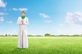 Asian muslim woman in veil praying on the green grass field
